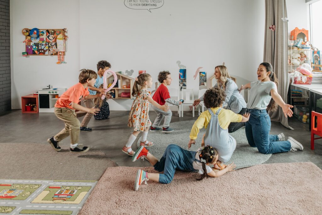 Kinder und Erzieherinnen spielen gemeinsam in einer bunten, vielfältigen Gruppe