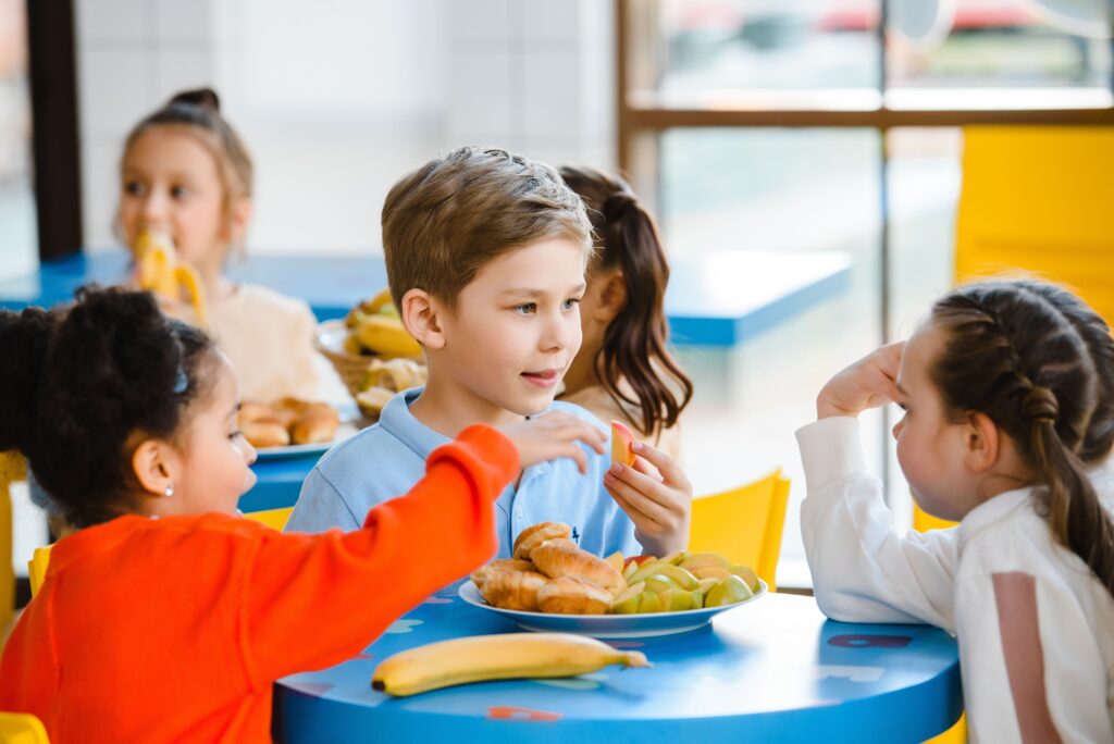 Kinder essen gemeinsam eine vielfältige, kultursensible Mahlzeit in der Kita