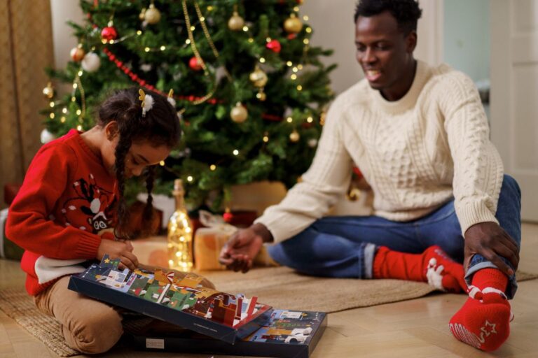 Kind und Elternteil öffnen gemeinsam ein Türchen am Adventskalender