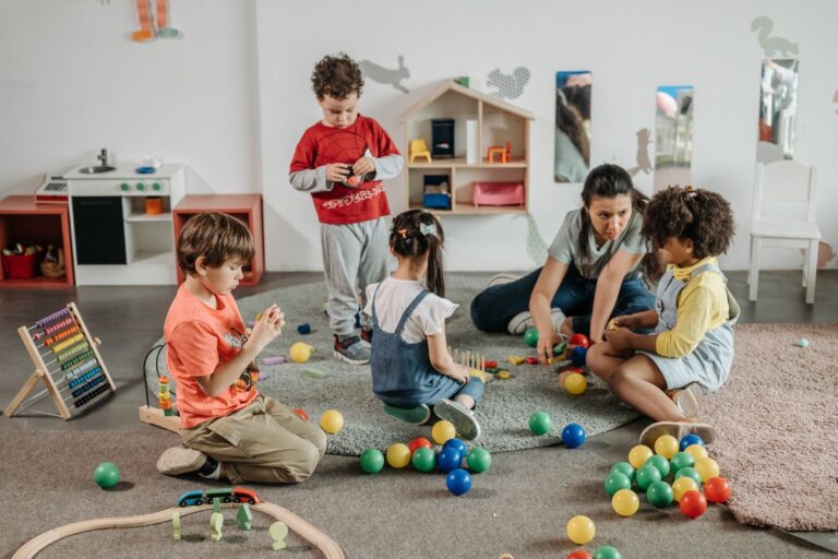 Kinder sitzen mit ihrer Erzieherin im Morgenkreis auf dem Boden